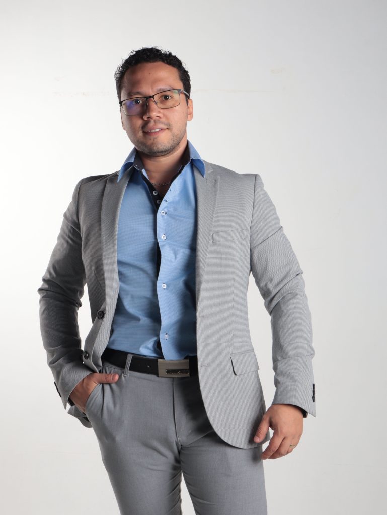 Confident man in grey suit and blue shirt poses for a professional portrait.